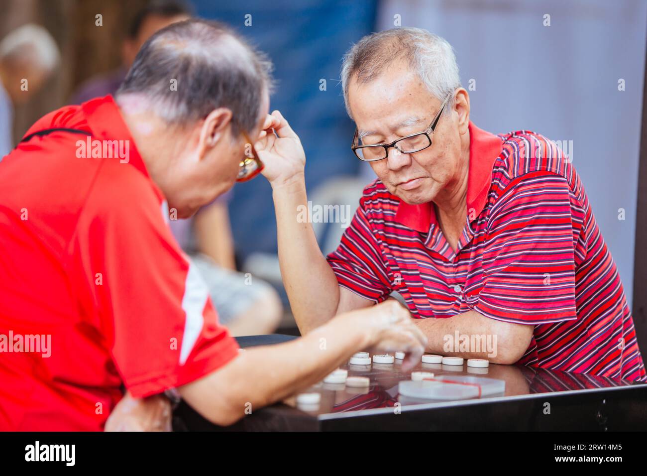 Chinatown, Singapore, June 21st 2015: Older Chinese men play Xiangqi, or Chinese Chess in a public space in SIngapore Stock Photo