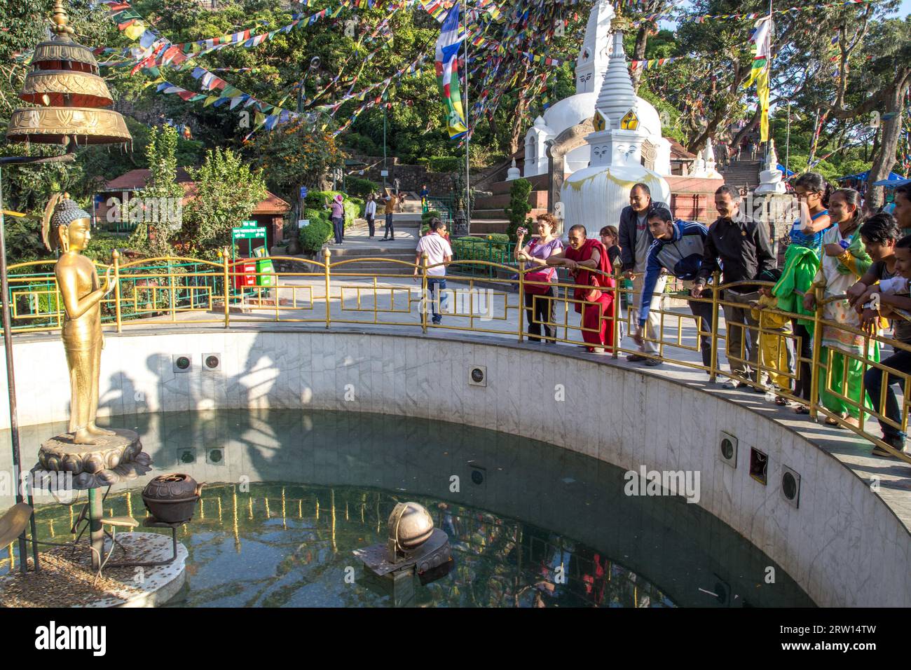 Kathmandu, Nepal, October 20, 2014: People throwing coins into a wishing well at Swayambhunath Stupa Stock Photo