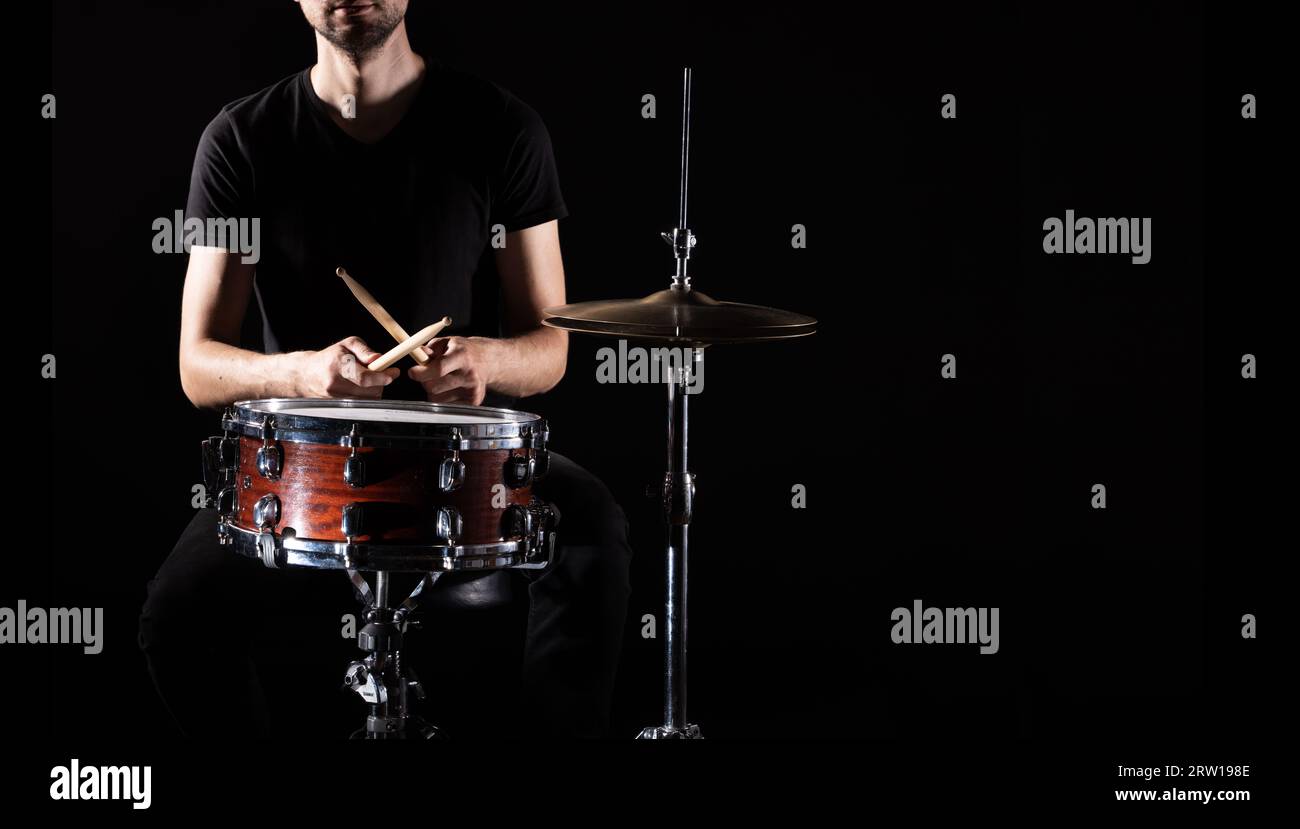 man plays musical percussion instrument with sticks closeup on a black