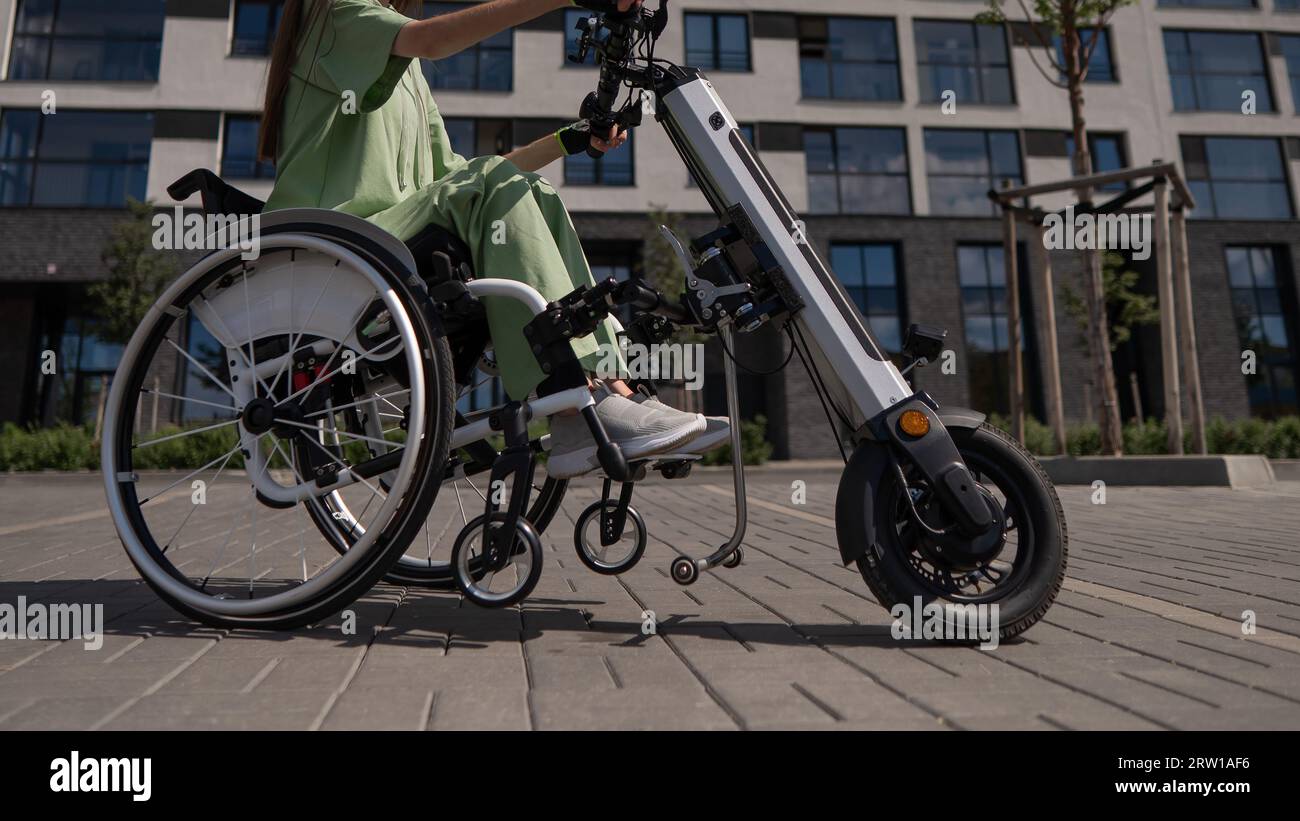 A woman in a wheelchair with an assistive device for manual control. Electric handbike Stock