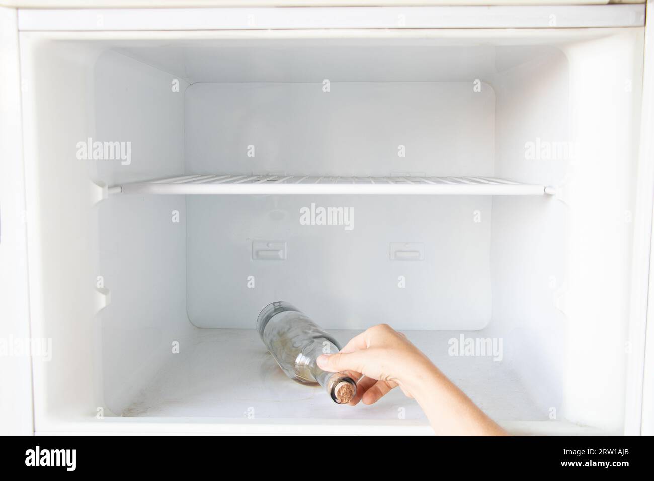 A woman's hand takes out a bottle of alcoholic drink from the freezer, bad habit and alcoholism, drinking alone, crisis Stock Photo