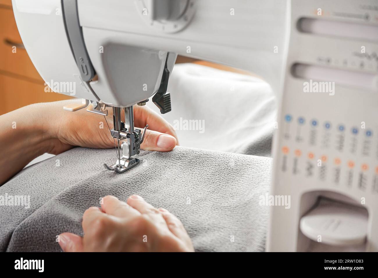 Tailor hands stitching gray fabric on modern sewing machine at ...