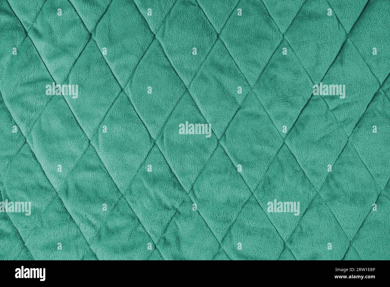 Quilted velours fabric background. Green texture blanket or puffer jacket, stiched with diamond pattern, soft wrinkled surface, crupmed textile Stock Photo