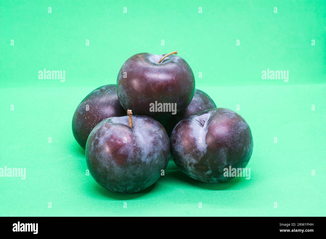 Ripe plums against a green background Stock Photo