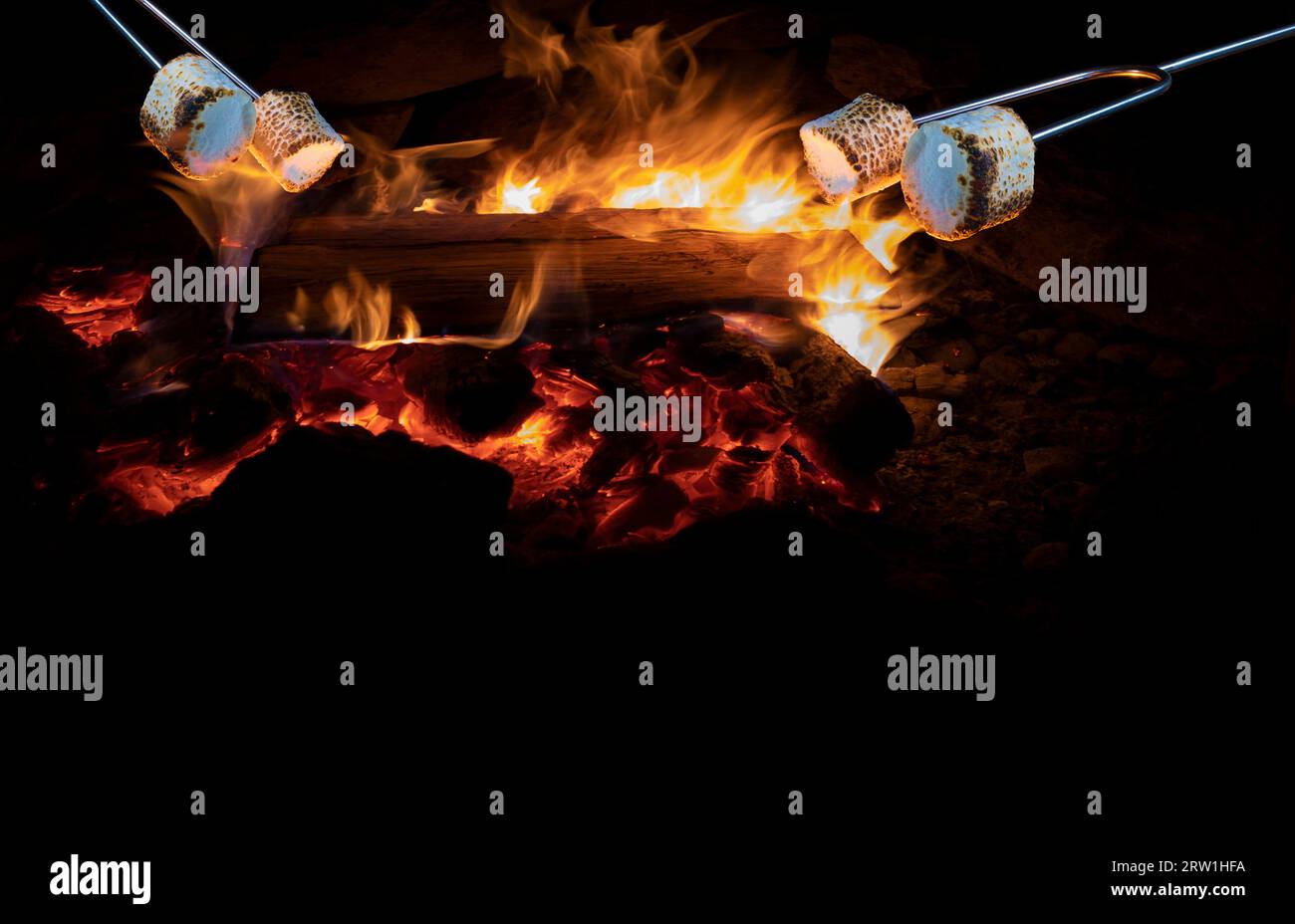 Marshmallows being licked by a campfire's flames at night with copy space below Stock Photo