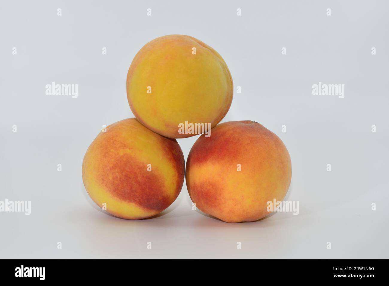 Peaches stacked in three on a white background. Stock Photo