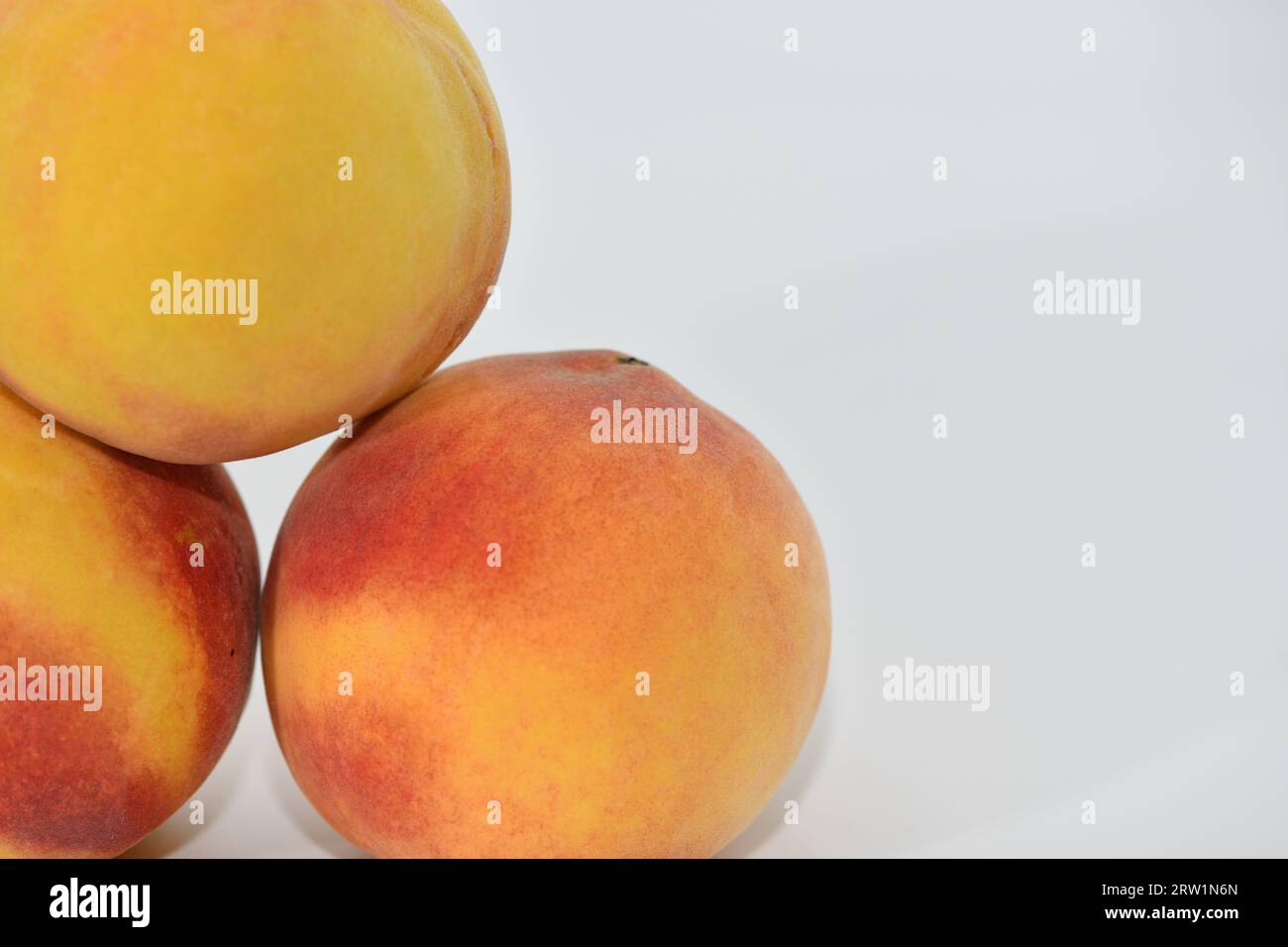 Peaches stacked in three on a white background. Stock Photo
