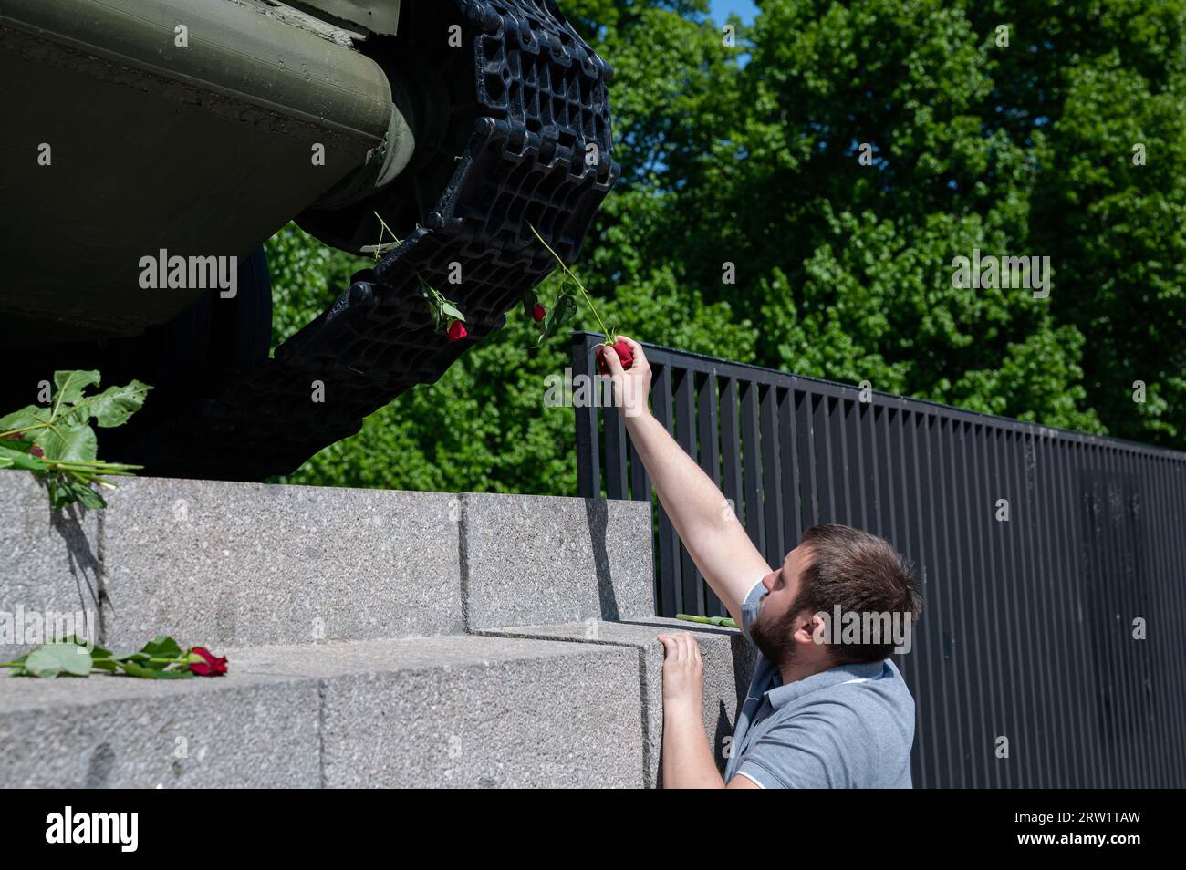 08.05.2022, Germany, Berlin, Berlin - Europe - A man inserts a red rose into the chain of a T-34 tank at the Soviet Memorial along the Strasse des 17. Stock Photo