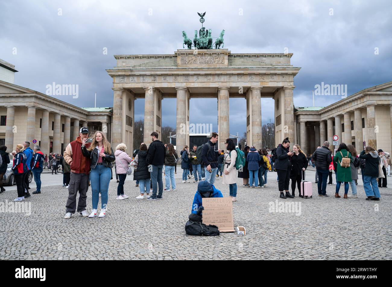 25.03.2023, Germany, Berlin, Berlin - Europe - A homeless man begs with a sign on Pariser Platz in front of the Brandenburg Gate in the Mitte district Stock Photo