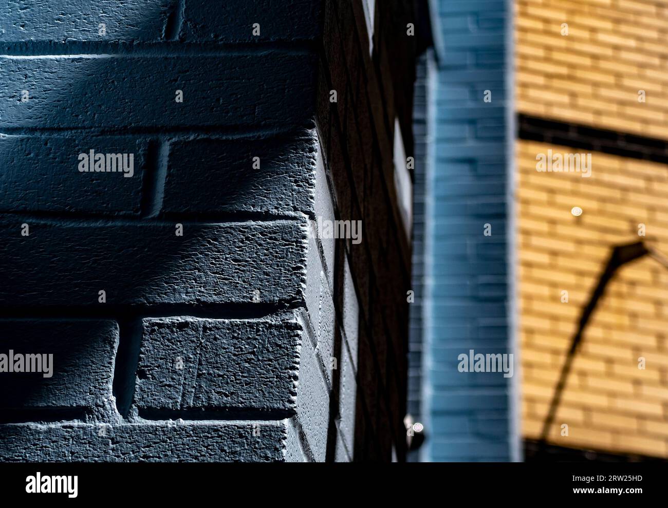 Shapes and shadows around a blue brick wall Stock Photo