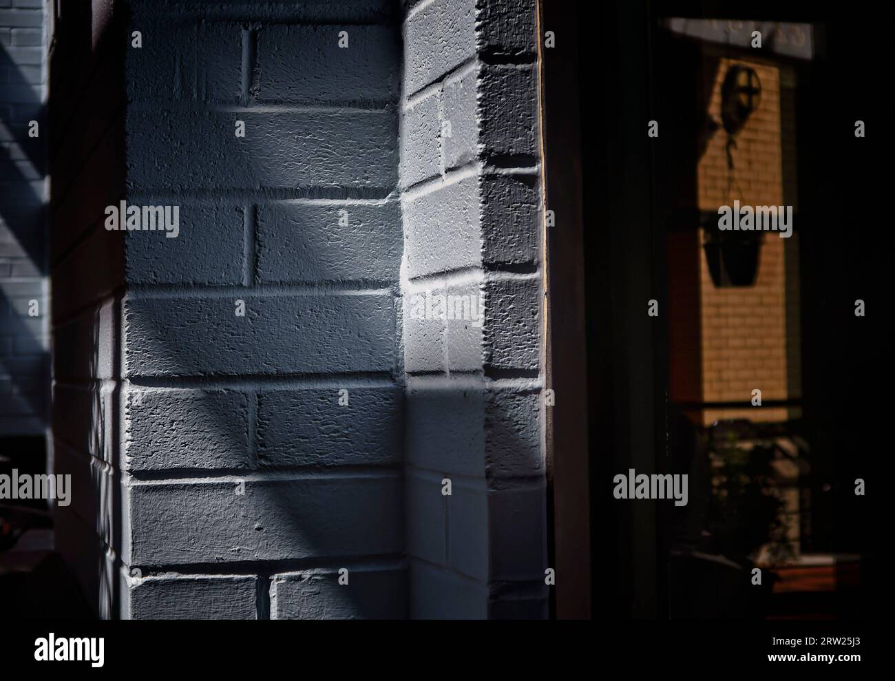 Shapes and shadows around a blue brick wall Stock Photo