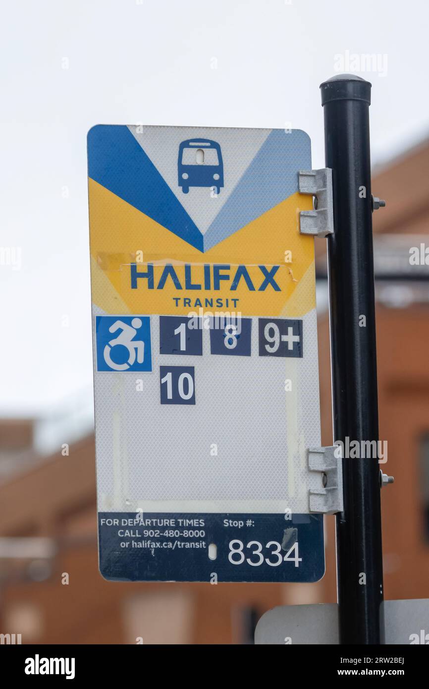 Halifax Transit bus stop information sign post with multiple bus route numbers, handicap access and stop number for tracking. HALIFAX, NOVA SCOTIA, CA Stock Photo