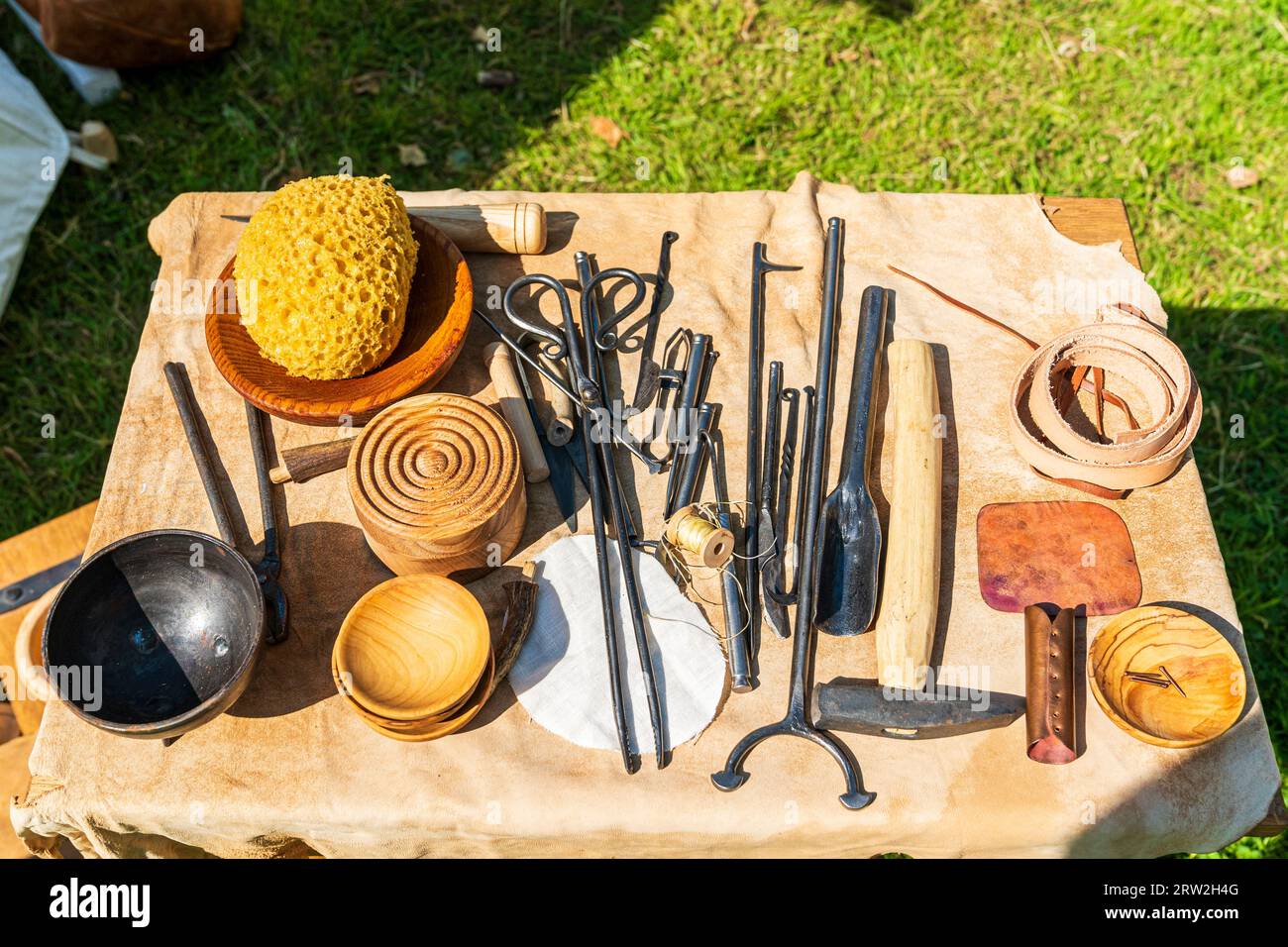 Top down view of medieval medical instruments on a table covered with a leather hide. Includes bowls, metal tools, and other surgical instruments. Stock Photo