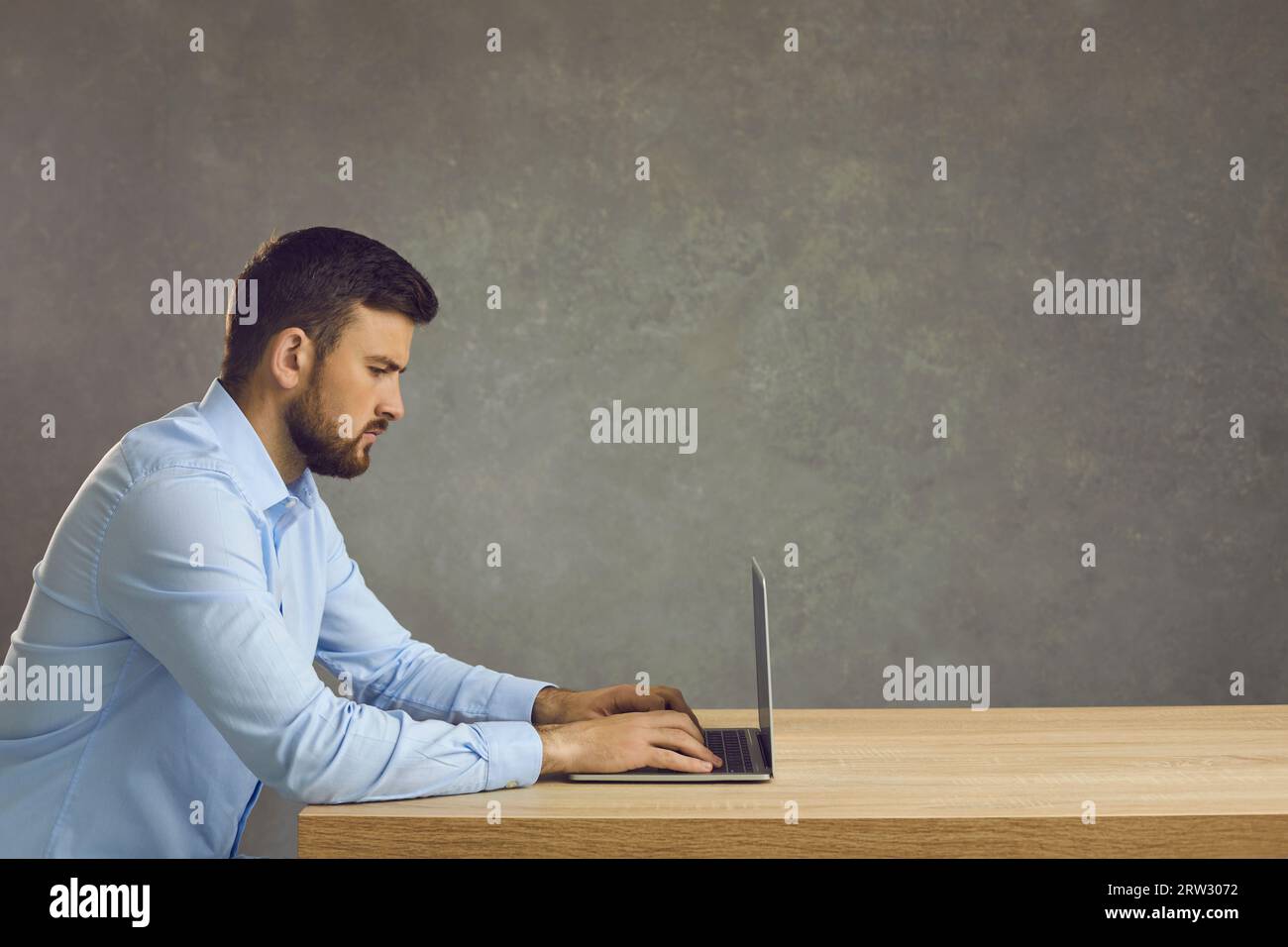 Serious focused smart programmer or employee working with laptop on deadline project. Stock Photo