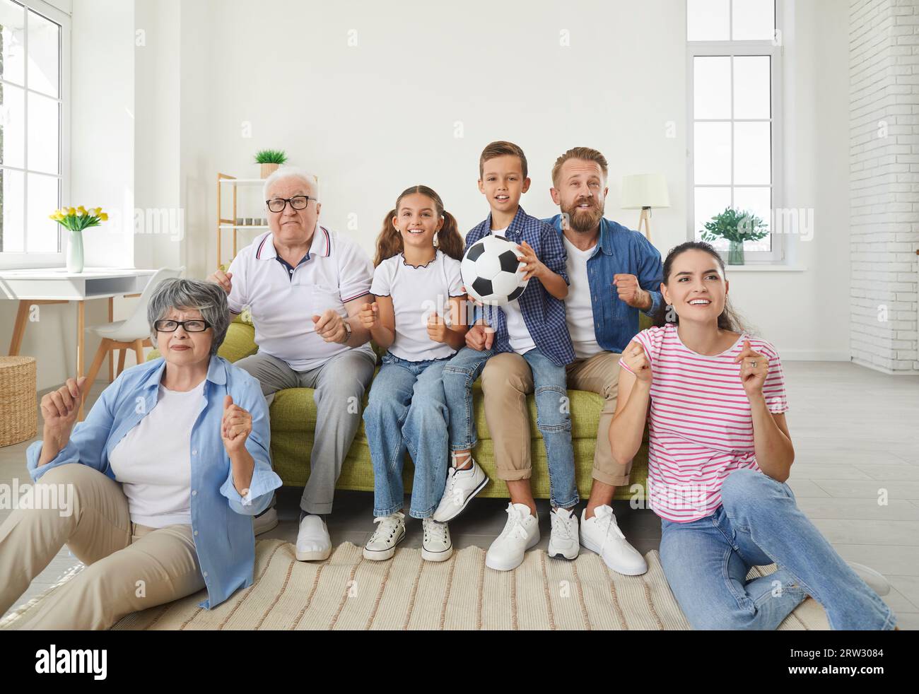 Happy big family watching soccer match on TV in living room at home Stock Photo