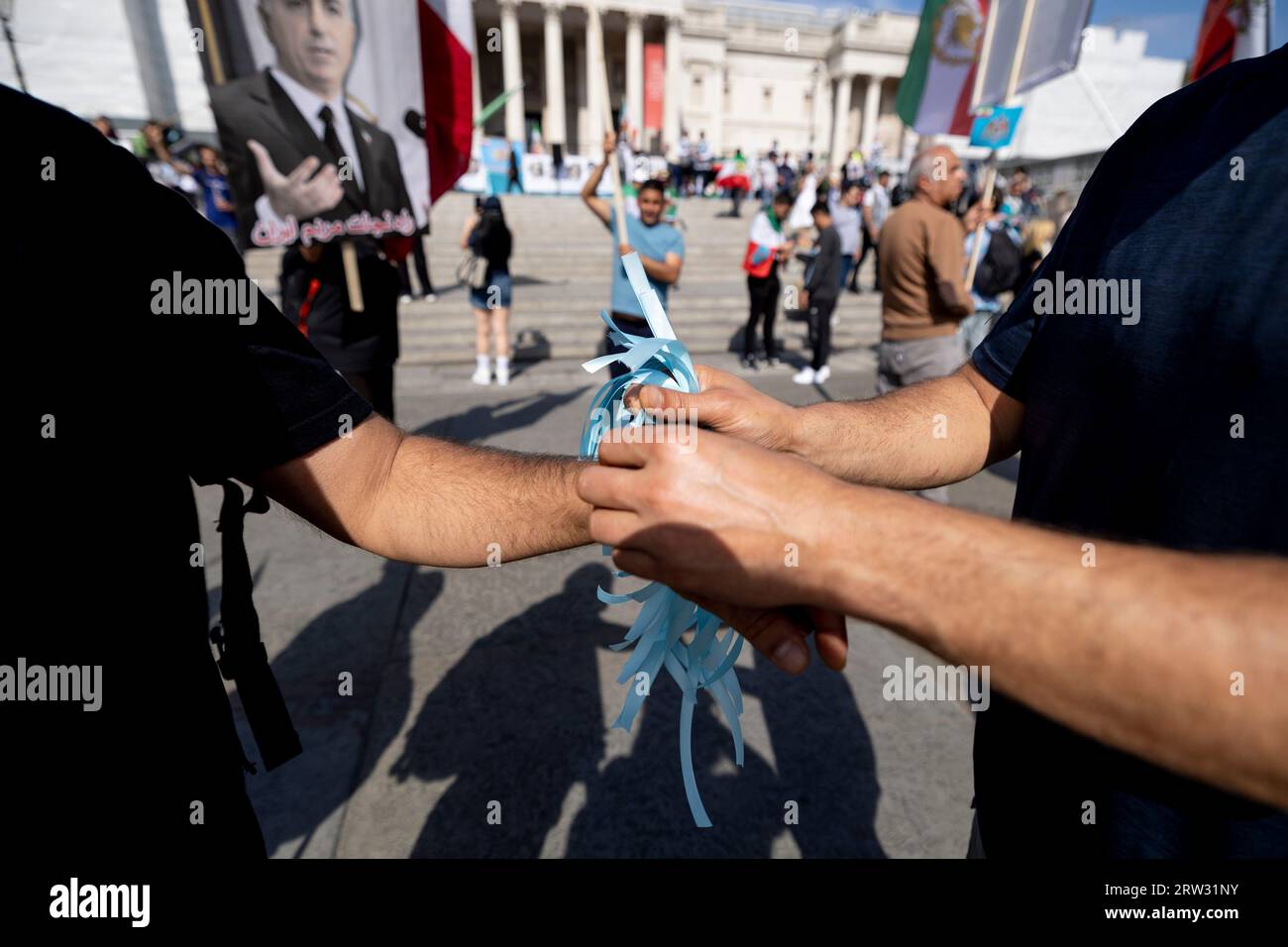 An Iranian protester is seen tying a blue ribbon on other protester's ...