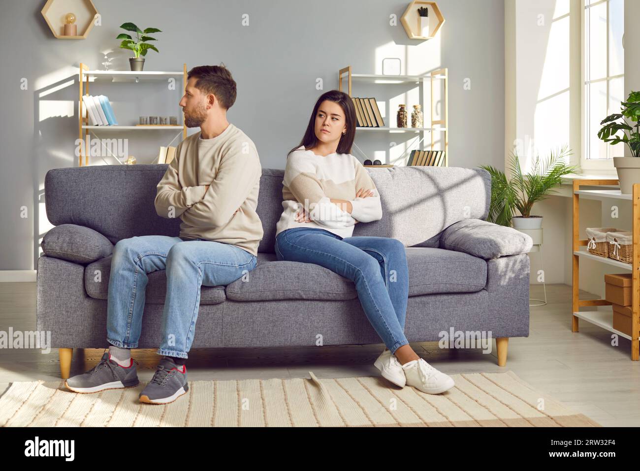 Young family couple having conflict and sitting back to back on couch after quarrel Stock Photo