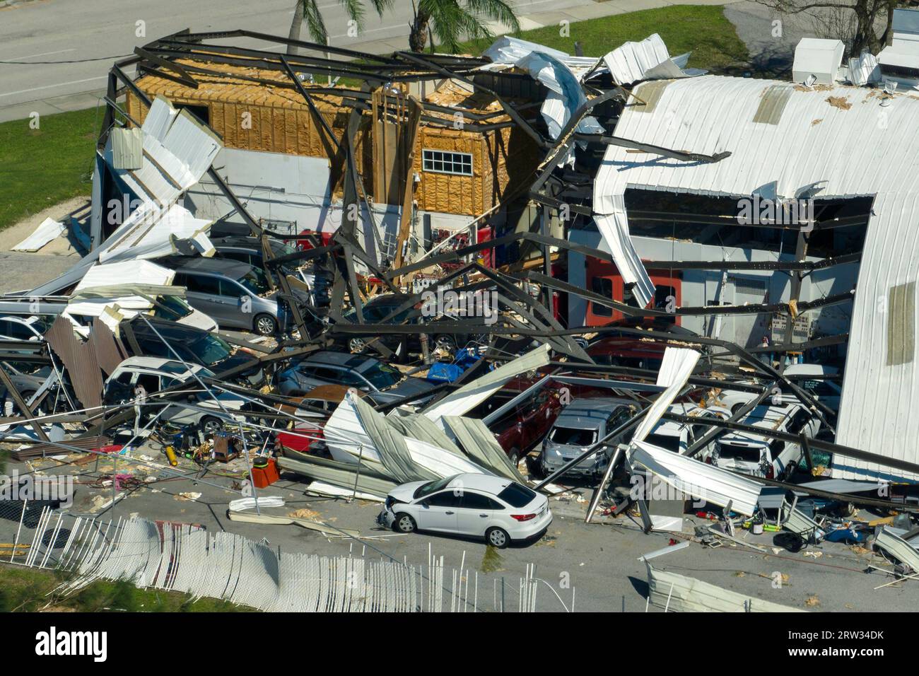 Car dealership building destroyed by hurricane with damaged cars under