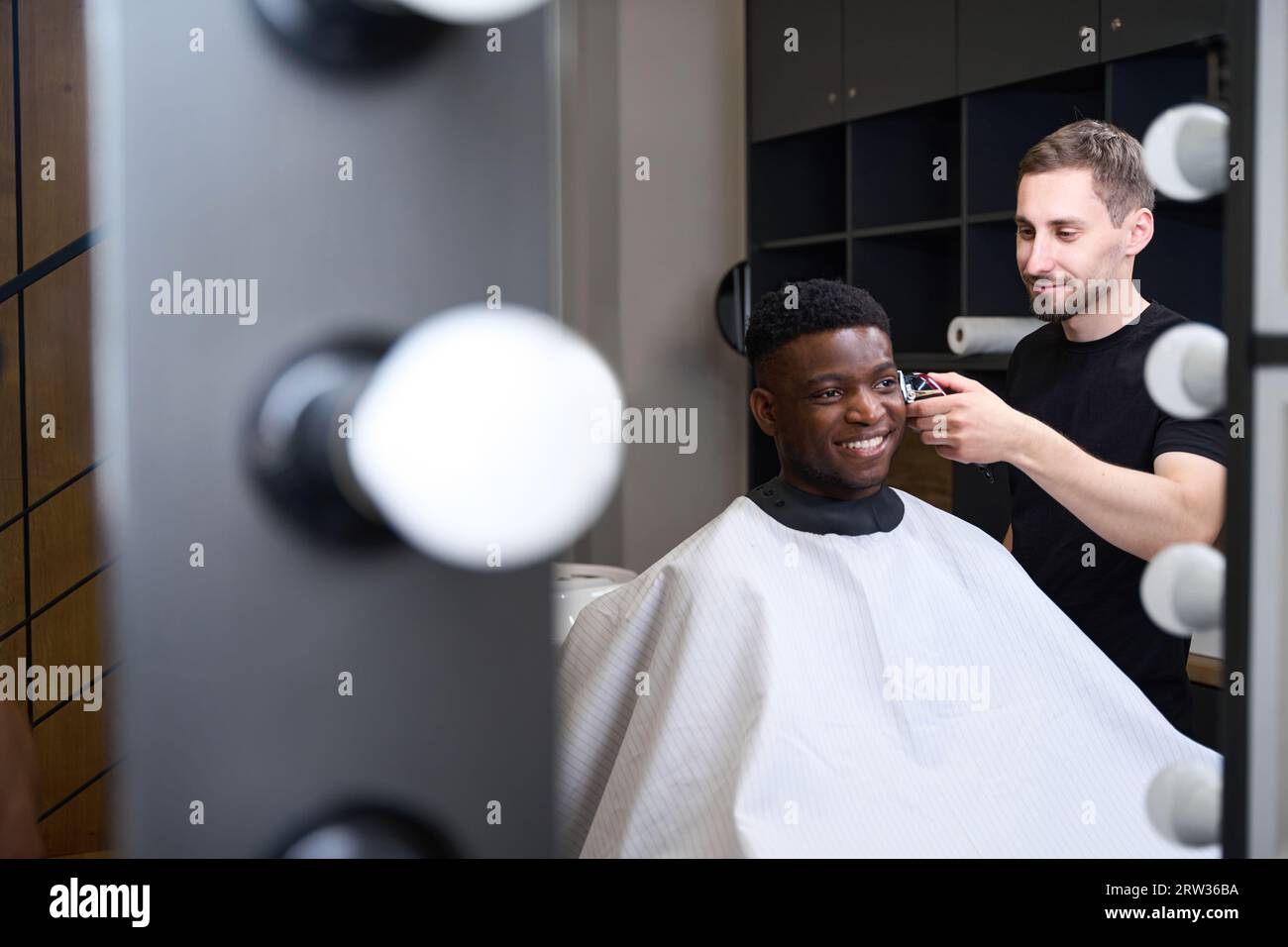 African American client sits in front of mirror in hairdressers chair