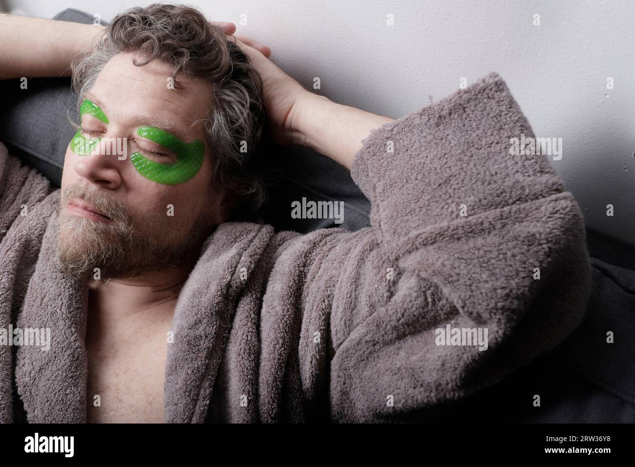 man in his forties with beard relaxed with moisturizing eye patches Stock Photo
