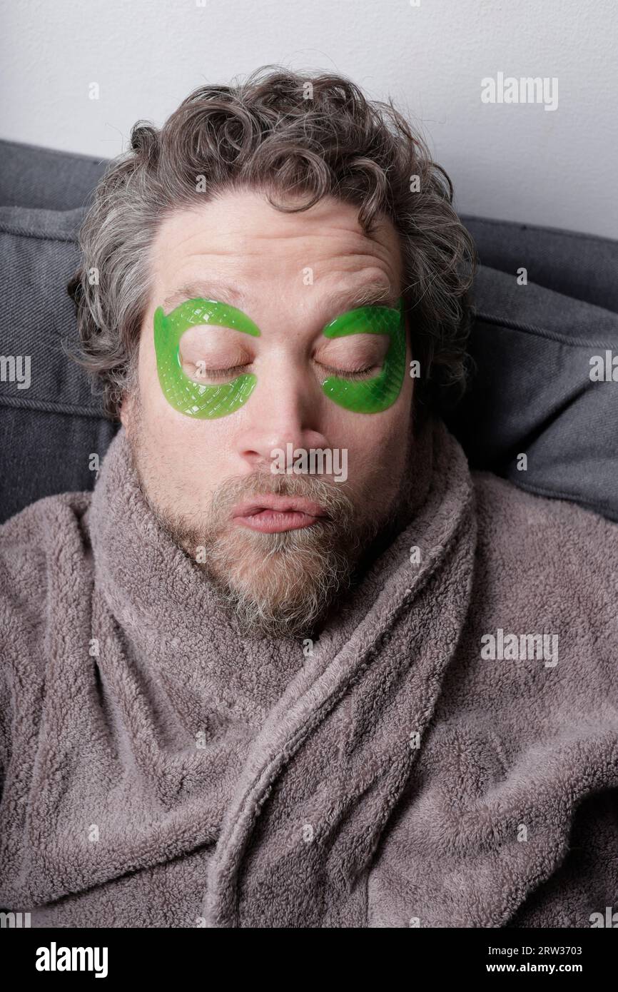 man in his forties with beard and moisturizing beauty pads on his eyes Stock Photo