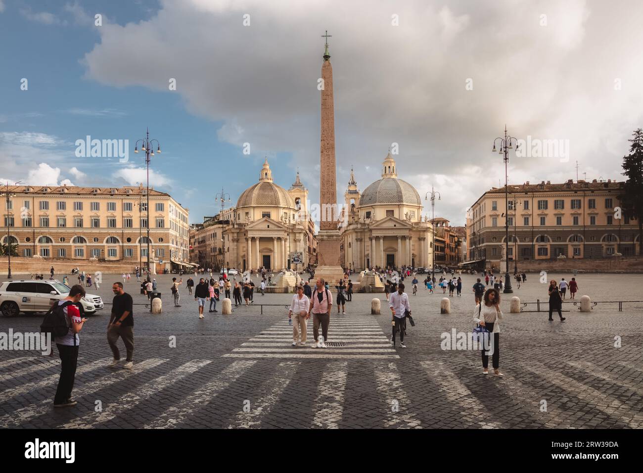 Rome, Italy - August 28, 2023: Tourists cross a pedestian crosswalk beside Baroque churches and an obelisk in the popular landmark Piazza del Popolo i Stock Photo