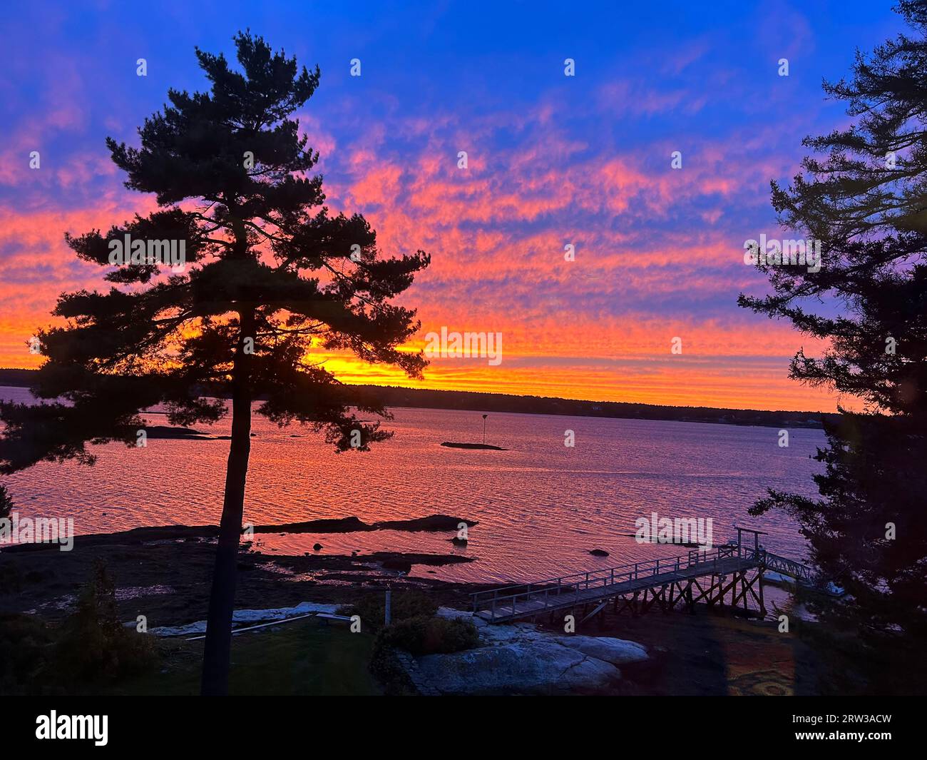 This photo was taken the night of September 15 (the night before Hurricane Lee hit the area). The sun is setting behind Westport Island. The view is from Sawyers Island in Boothbay, Maine. The waterway is the Sheepscot River. Stock Photo