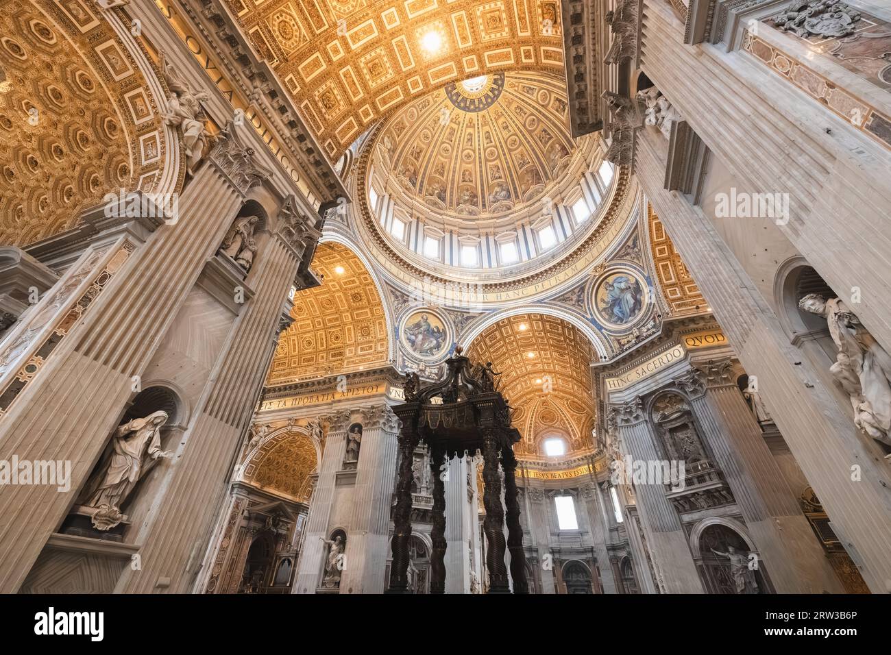 Extravagant interior and vaulted ceiling dome above Bernini's Baldacchino altarpiece inside Saint Peter's Basilica, home of the Roman Catholic Church Stock Photo
