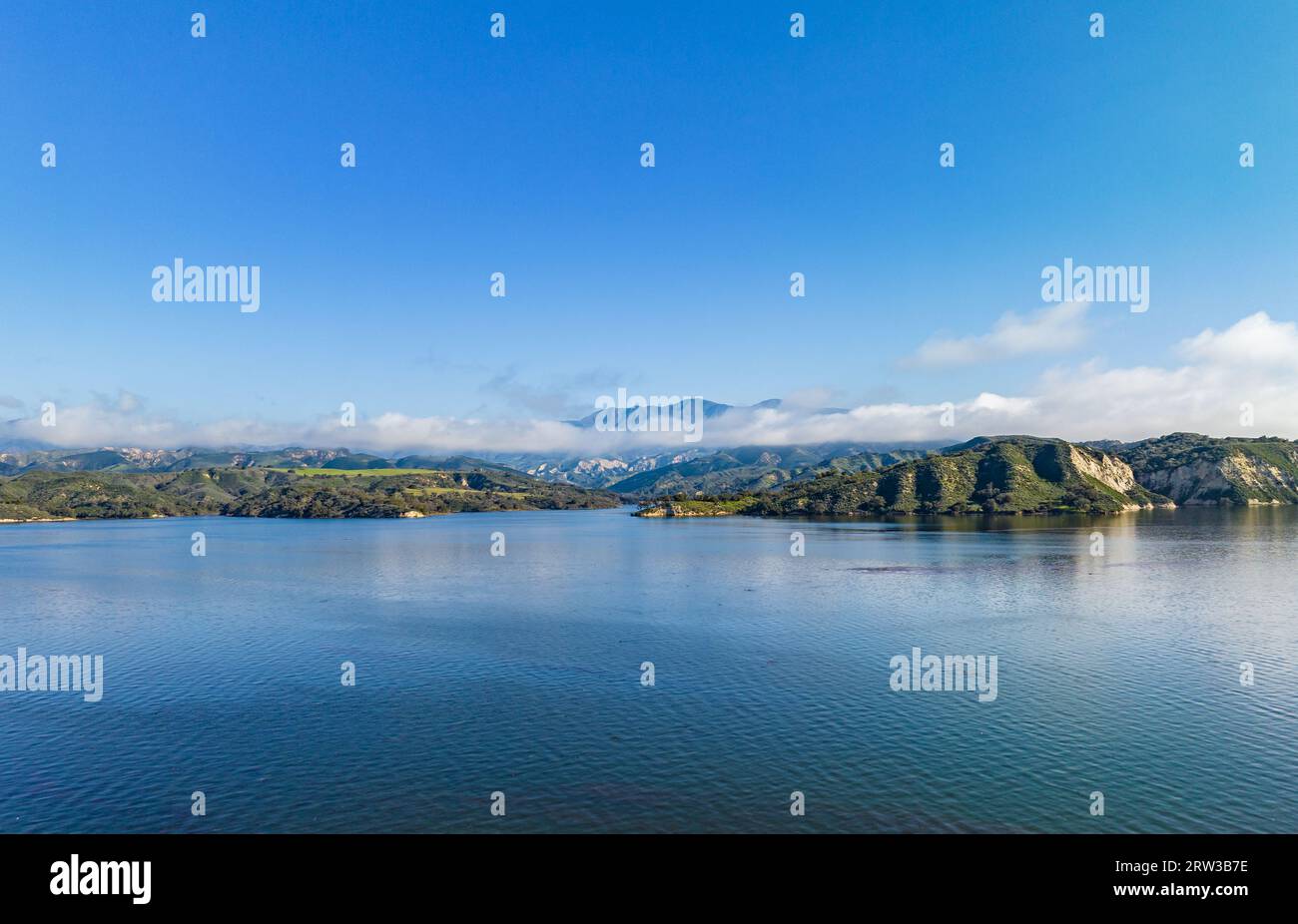 Aerial panoramic shot of lake water surface and mountains shrouded in clouds in distance. Amazing landscape photo. Cachuma Lake, California, USA Stock Photo