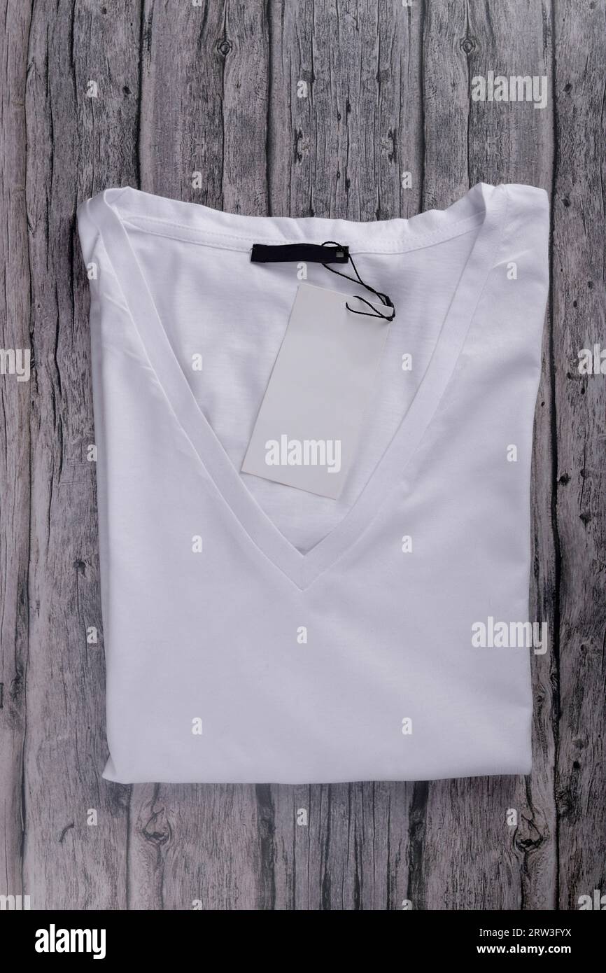 flat law of white V-neck t-shirt folded with label on vintage gray wood Stock Photo