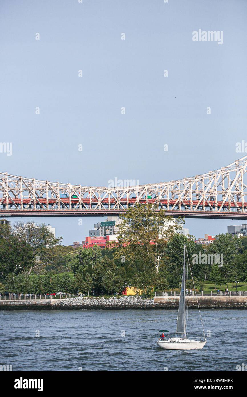 New York, New York, USA. 16th Sep, 2023. Sailboat passes on a sunny day on the East River in New York City with the Queensborough Bridge and a smokestack from Ravenswood power station in background. (Credit Image: © Bianca Otero/ZUMA Press Wire) EDITORIAL USAGE ONLY! Not for Commercial USAGE! Stock Photo