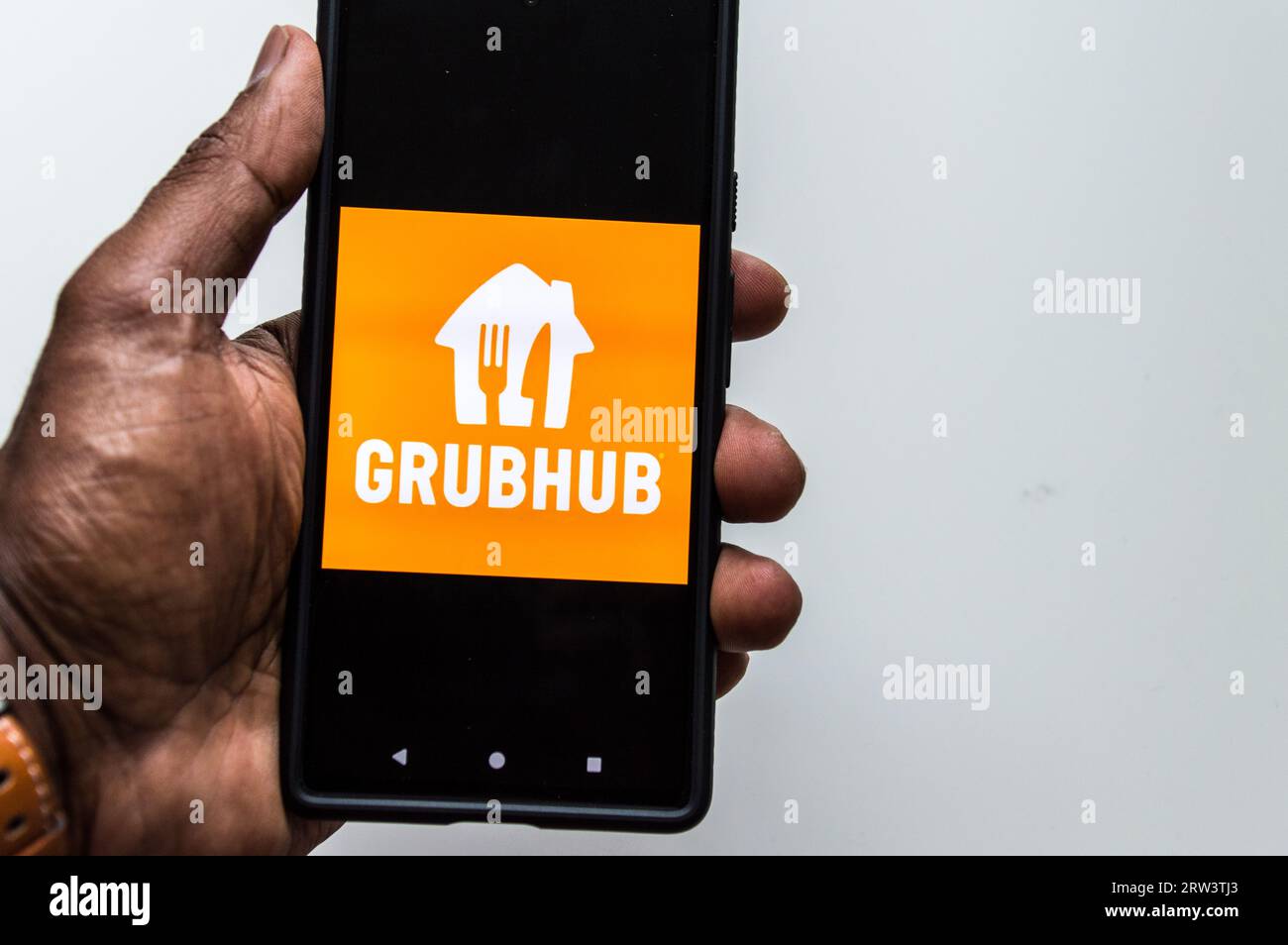 Adult male looking at Grubhub prepared food delivery app on smartphone Stock Photo