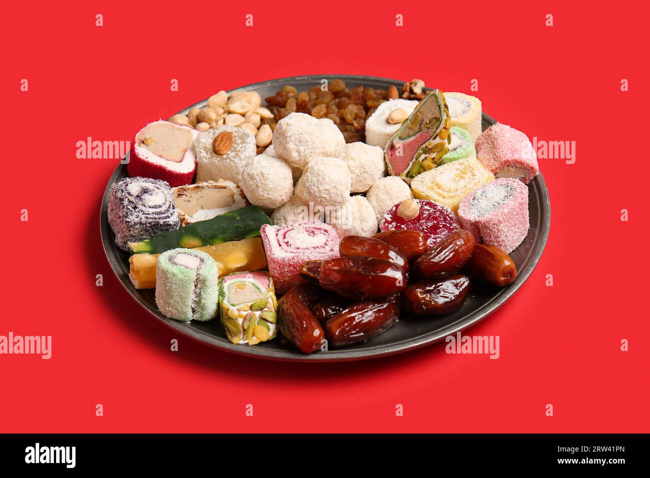 Plate with different tasty treats on red background. Divaly celebration Stock Photo