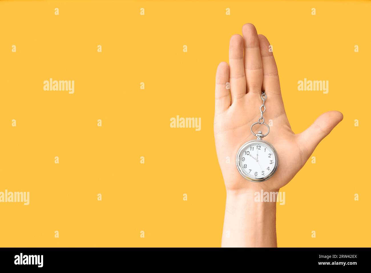 Female hand holding pocket watch on yellow background Stock Photo Alamy