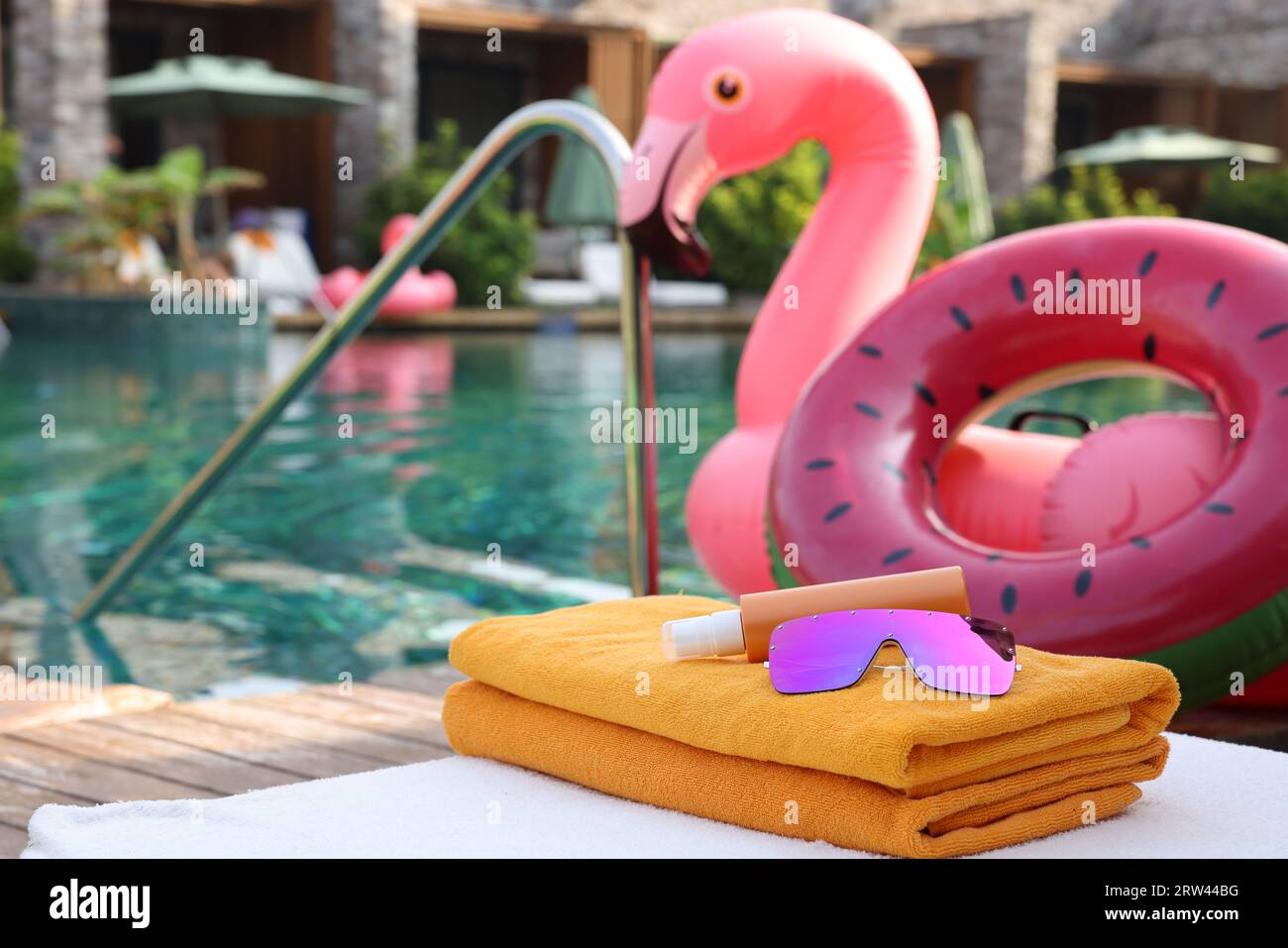 Beach accessories on sun lounger, inflatable ring and float near outdoor swimming pool at luxury resort Stock Photo