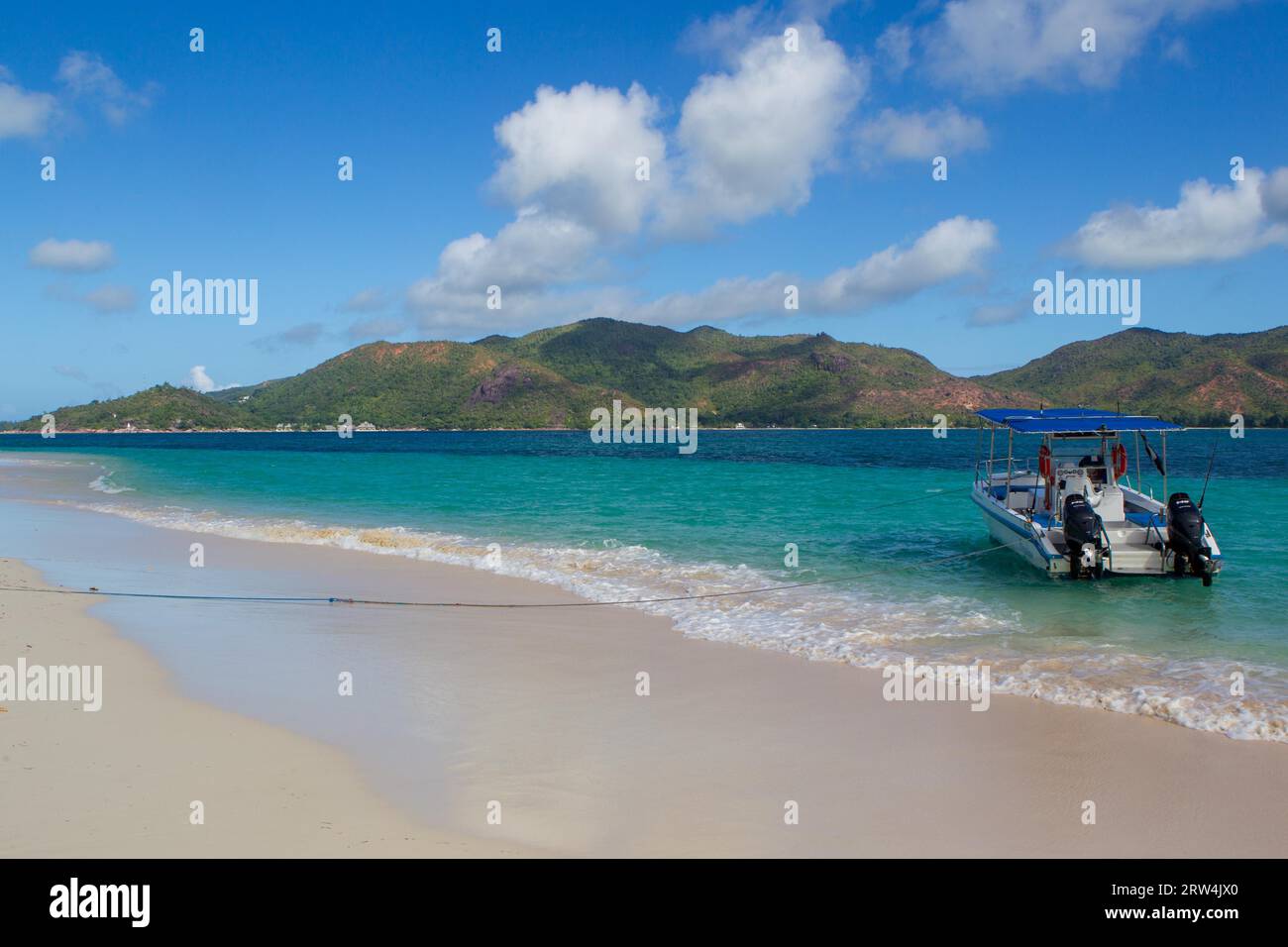 Excursion boats on Curieuse beach overlooking Praslin, Seychelles Stock Photo