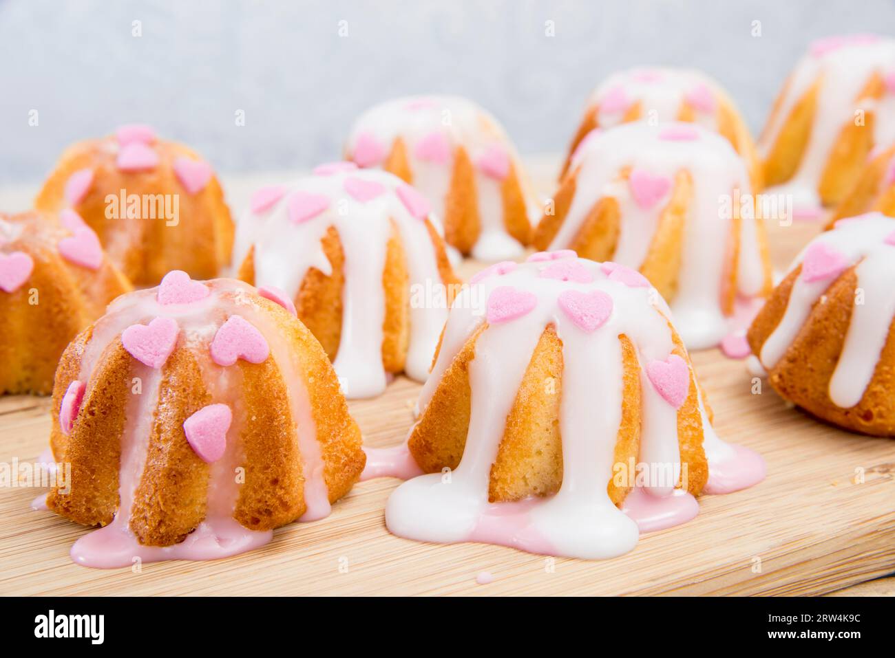 Small sponge cake glazed with icing and sprinkled hearts Stock Photo
