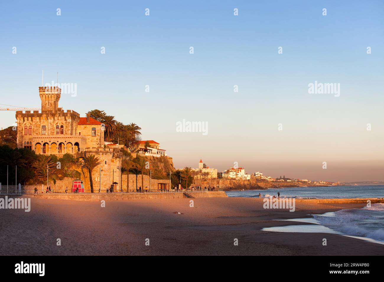 Tranquil scenery by the Atlantic Ocean, Tamariz Beach overlooked by a castle at sunset in resort town of Estoril in Portugal Stock Photo