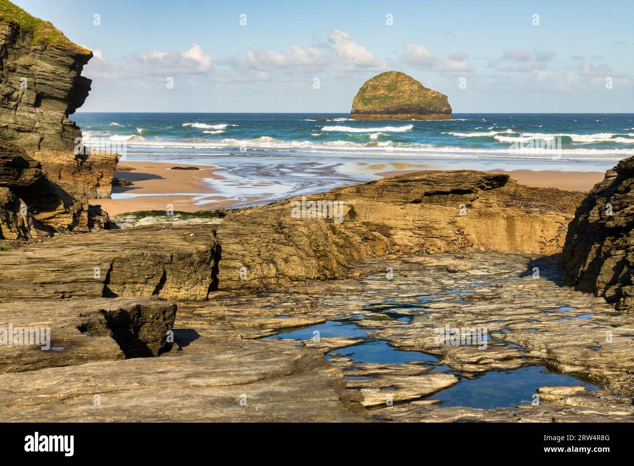 The rocky entrance to the beach at Trebarwith Strand, Cornwall, and the small island of Gull Rock. Stock Photo