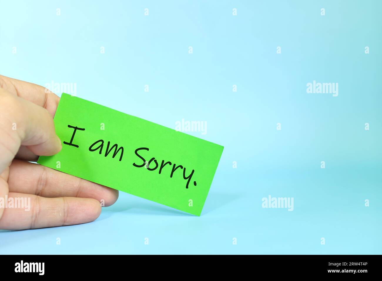 I am sorry message concept. Hand holding a bright yellow paper with written message note Stock Photo