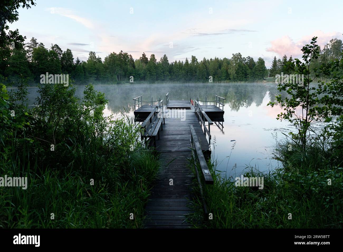 Beautiful wooden pier on a small lake Suur Linajarv in the morning light and fog, near Mannikjarve hiking trail in Endla nature reserve, Estonia Stock Photo