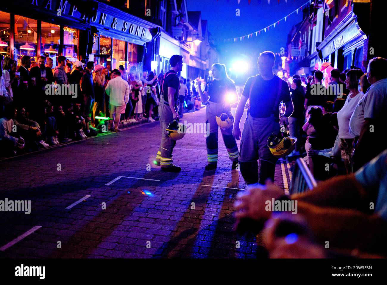 Ringwood, Hampshire, UK, 16th September 2023: Members of the fire brigade ahead of their engine in the evening carnival procession along the high street. Paul Biggins/Alamy Live News Stock Photo