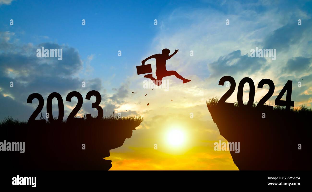 Welcome merry Christmas and Happy new year in 2024. Man jumping across the gap from 2023 to 2024 cliff with Sunset and Twilight Sky background. Stock Photo