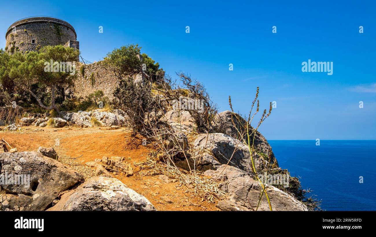 Torre Picada tower stands tall atop the cliffs of Port de Sóller, its imposing walls are a testament to the strategic fortification it once offered ag Stock Photo