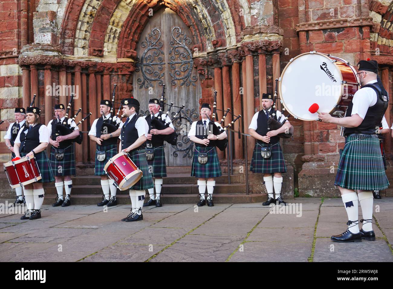 Bagpipers and drummers from the Kirkwall City Pipe Band perform in front of the historic St. Magnus Cathedral, Kirkwall, Orkney Island, Scotland Stock Photo