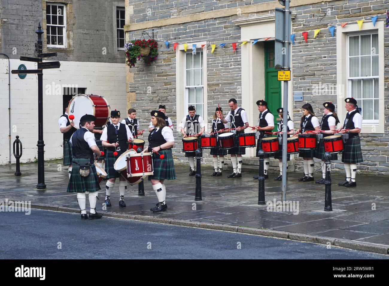 Male and female drummers from the Kirkwall City Pipe Band warm up before joining the group's bagpipers for a performance in the city center nearby Stock Photo