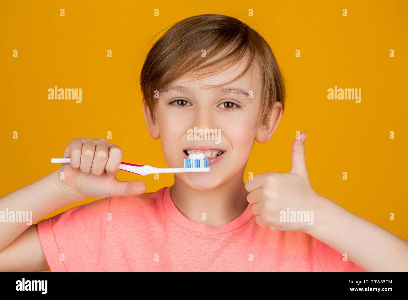 Boy toothbrush white toothpaste. Joyful child shows toothbrushes, shows a thumbs up. Little boy cleaning teeth. Dental hygiene. Happy little kid Stock Photo