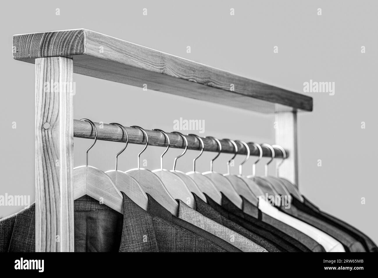 Suits for men hanging on the rack. Mens suits in different colors hanging on hanger in a retail clothes store, close-up. Black and white Stock Photo