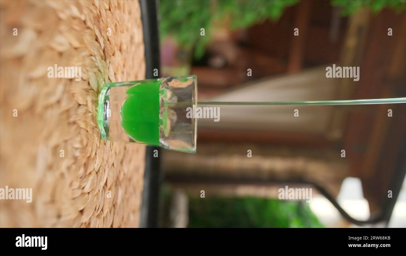 Vertical shooting of pouring liquid into glass. Clip. High green liquid