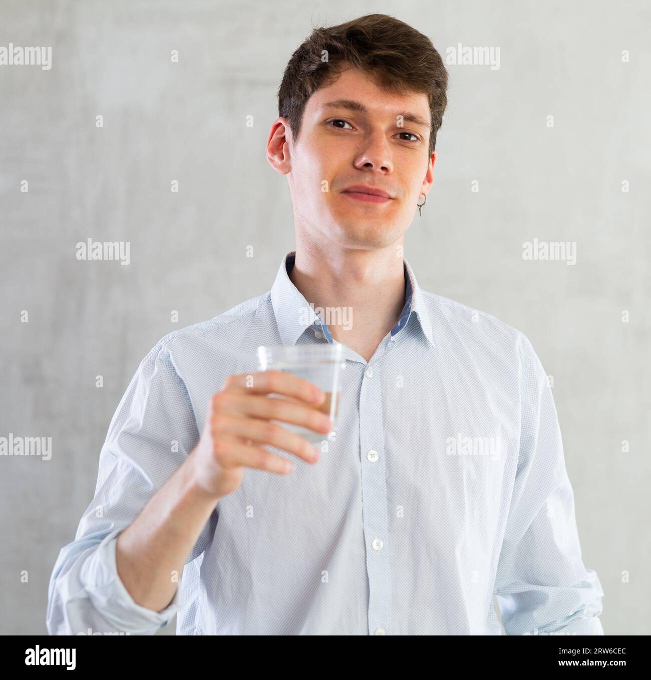 Positive young man drinking water from glass Stock Photo - Alamy